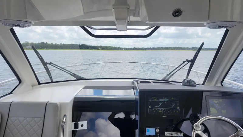  Yacht Photos Pics 2023 Pursuit OS 325 Offshore boat interior with dashboard view over calm waters.