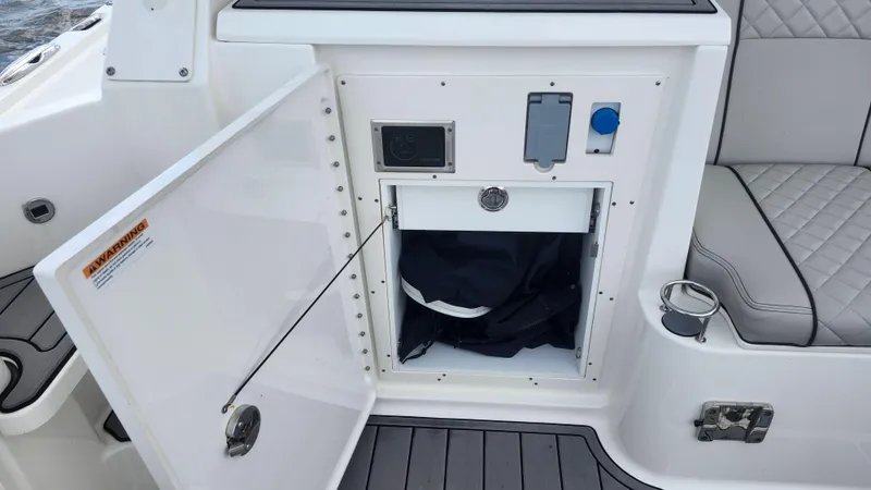  Yacht Photos Pics 2023 Pursuit OS 325 Offshore boat storage compartment with open door and seating area.