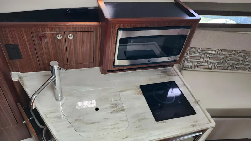  Yacht Photos Pics 2023 Pursuit OS 325 Offshore boat kitchen with sink, microwave, and cooktop.