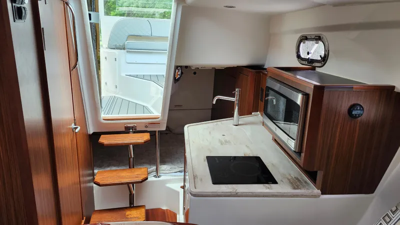  Yacht Photos Pics 2023 Pursuit OS 325 Offshore interior with modern kitchen and wooden accents.