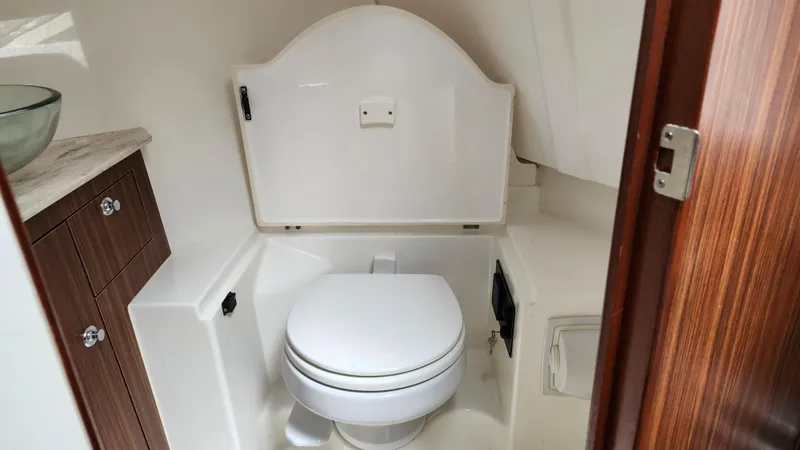  Yacht Photos Pics 2023 Pursuit OS 325 Offshore boat bathroom with toilet and wooden cabinetry.