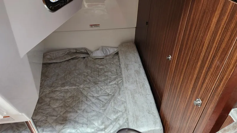  Yacht Photos Pics 2023 Pursuit OS 325 Offshore cabin interior with bed and wooden cabinetry.