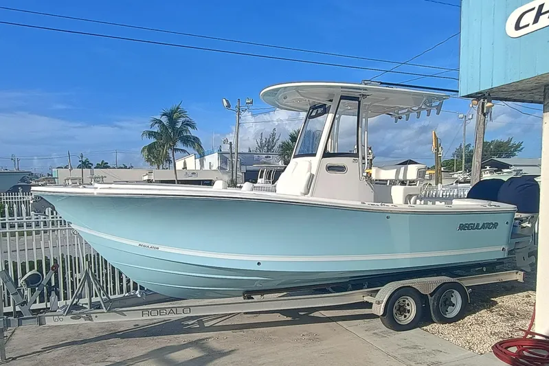  Yacht Photos Pics 2025 Regulator 23 boat on trailer, light blue hull, parked outdoors.