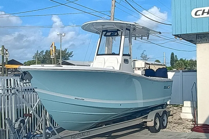  Yacht Photos Pics 2025 Regulator 23 boat on trailer, light blue hull, parked outdoors.