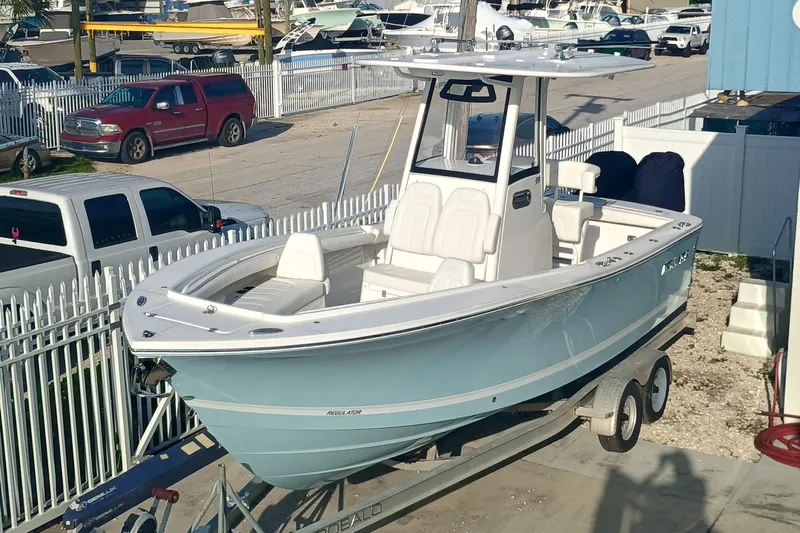  Yacht Photos Pics 2025 Regulator 23 boat on trailer, parked in marina lot with surrounding vehicles.
