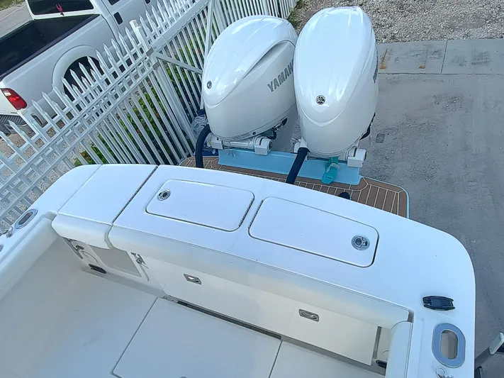 23-374 Yacht Photos Pics 2025 Regulator 23 boat with dual Yamaha outboard engines, parked near a white fence.