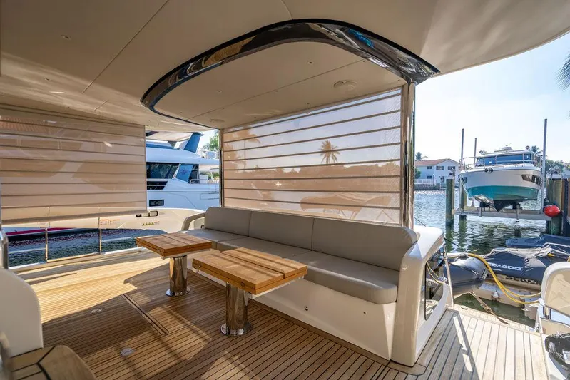 Kingship Yacht Photos Pics Luxurious 2023 Absolute 64 Navetta yacht deck with seating and wooden tables.