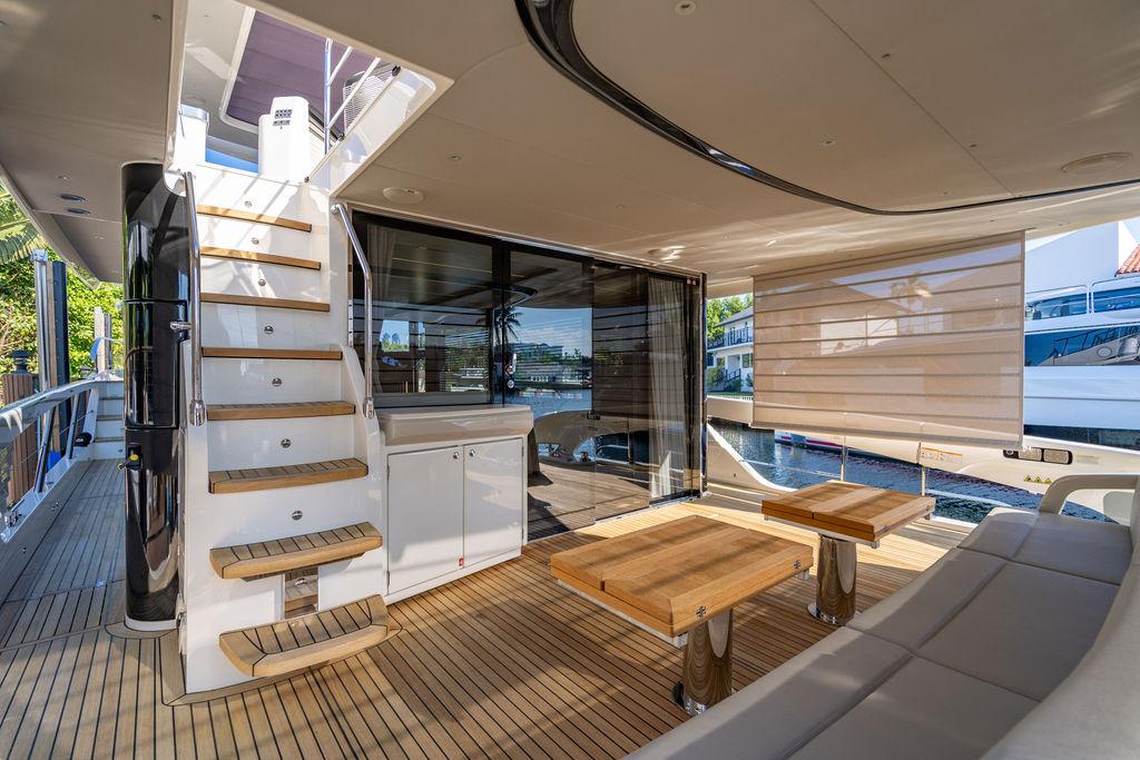 Luxurious 2023 Absolute 64 Navetta yacht interior with wooden deck and modern seating area.