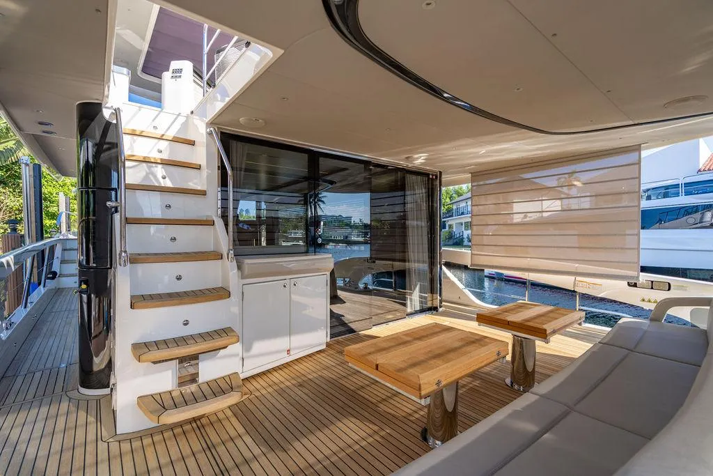 Luxurious 2023 Absolute 64 Navetta yacht interior with wooden deck and modern seating area.