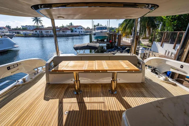 Kingship Yacht Photos Pics Luxury Absolute 64 Navetta yacht deck with wooden table, 2023 model, docked by waterfront homes.