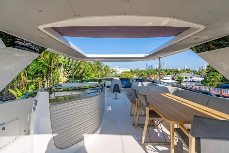 Kingship Yacht Photos Pics Luxurious 2023 Absolute 64 Navetta yacht deck with dining area and scenic views.