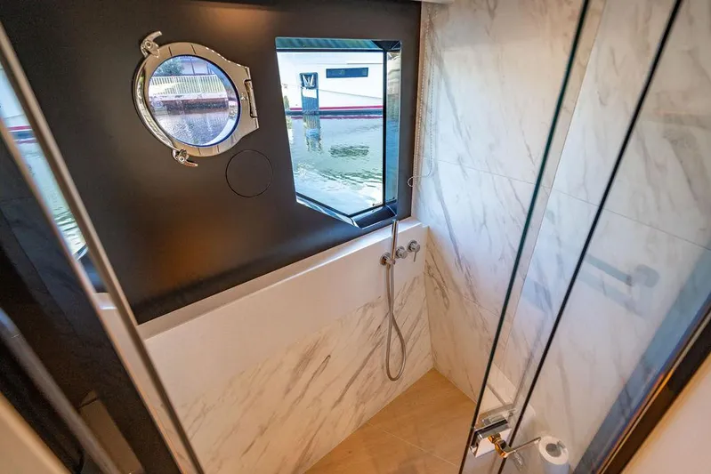 Kingship Yacht Photos Pics Luxurious bathroom on 2023 Absolute 64 Navetta yacht with marble walls and porthole window.