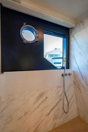 Kingship Yacht Photos Pics Luxurious bathroom on 2023 Absolute 64 Navetta yacht with marble walls and porthole window.