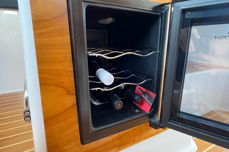Motivated Yacht Photos Pics Open wine cooler on 2022 Cutwater C-32 CB boat, showcasing wine bottles inside.