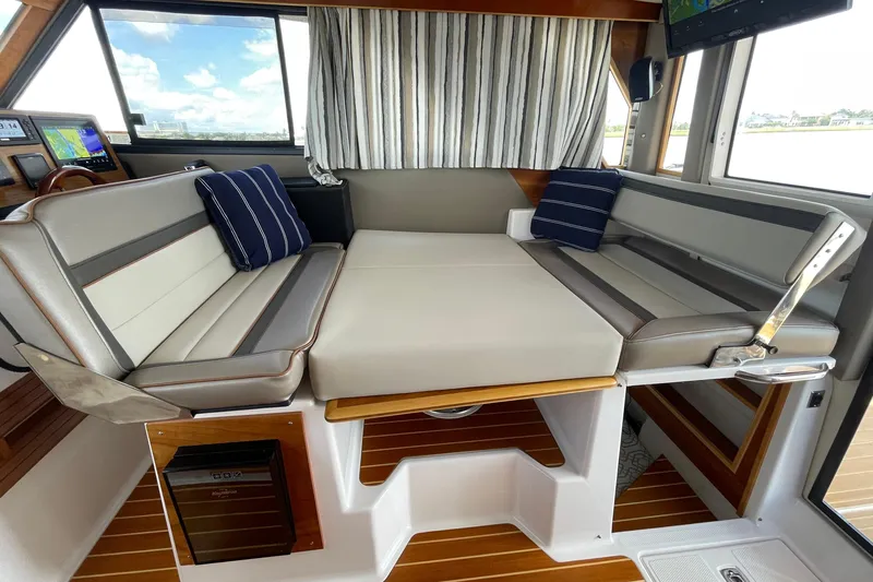 Motivated Yacht Photos Pics Interior of 2022 Cutwater C-32 CB boat with convertible seating and striped cushions.