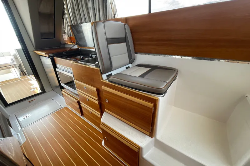 Motivated Yacht Photos Pics 2022 Cutwater C-32 CB interior with wood cabinetry, cushioned seating, and modern appliances.