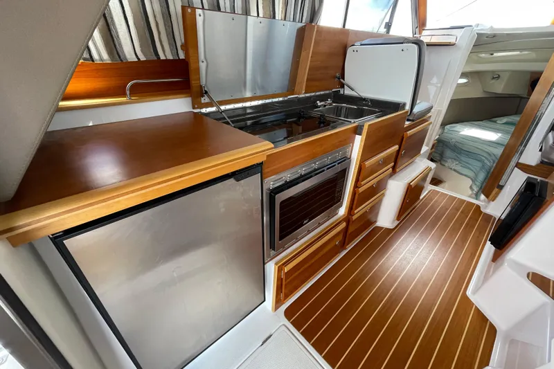 Motivated Yacht Photos Pics 2022 Cutwater C-32 CB interior with kitchenette, wood cabinetry, and compact design.