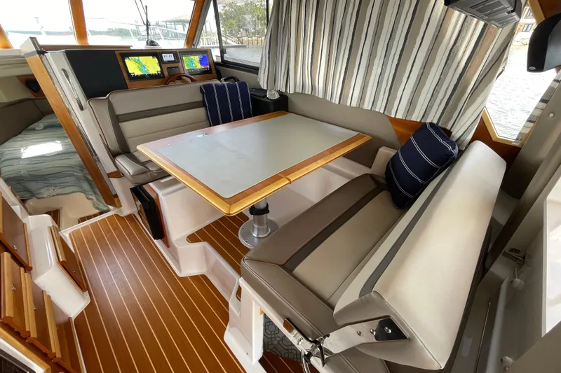 Motivated Yacht Photos Pics 2022 Cutwater C-32 CB interior with dining area, striped cushions, and navigation screens.