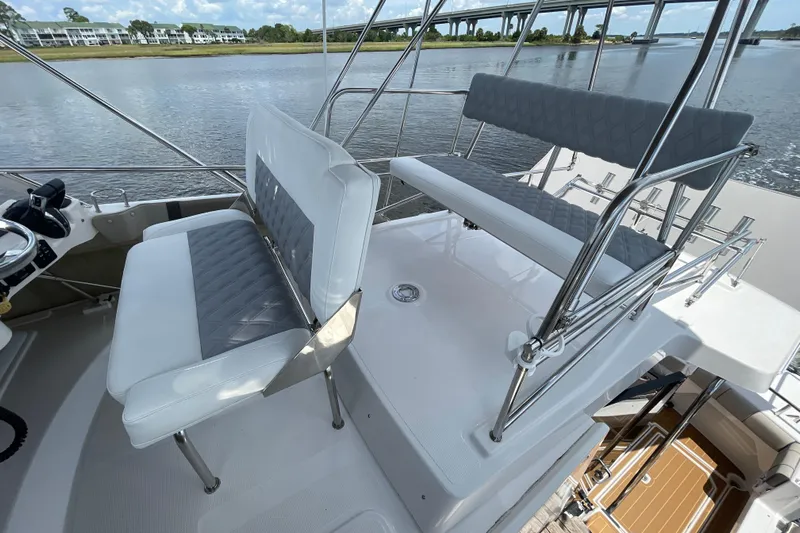 Motivated Yacht Photos Pics 2022 Cutwater C-32 CB boat with dual seating on the deck, overlooking a scenic waterway.
