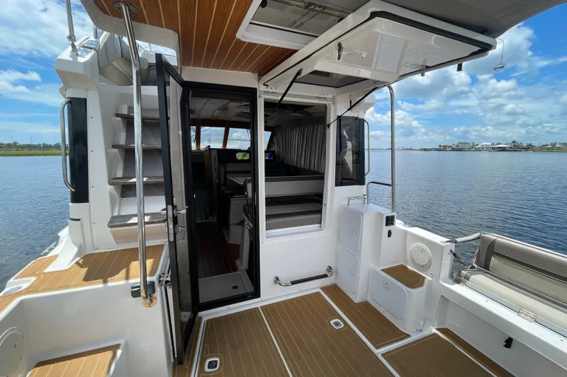 Motivated Yacht Photos Pics 2022 Cutwater C-32 CB boat interior with open door, wooden flooring, and water view.