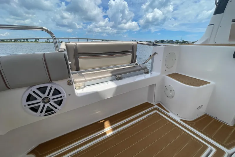 Motivated Yacht Photos Pics 2022 Cutwater C-32 CB boat interior with cushioned seating and marine speaker, under a cloudy sky.