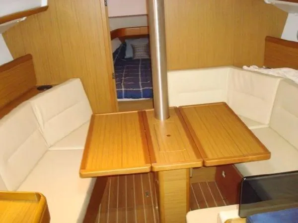 For Grins Too Yacht Photos Pics Interior of 2010 Jeanneau Sun Odyssey 36i sailboat with wooden table and seating.