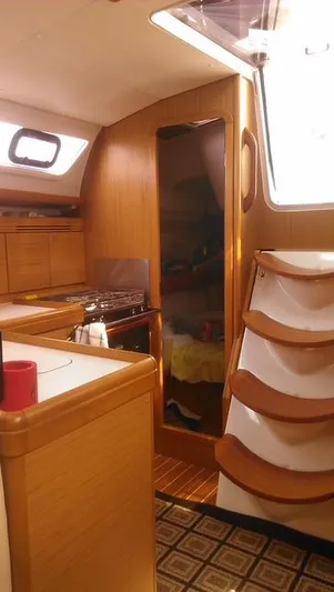 For Grins Too Yacht Photos Pics Interior of 2010 Jeanneau Sun Odyssey 36i sailboat, featuring wooden cabinetry and compact kitchen area.