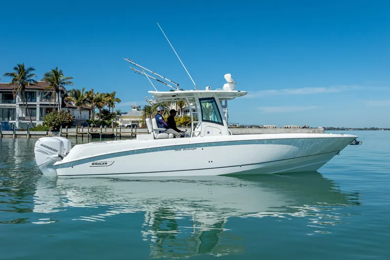 High Voltage Yacht Photos Pics 2013 Boston Whaler 320 Outrage boat on calm water, with palm trees in background.