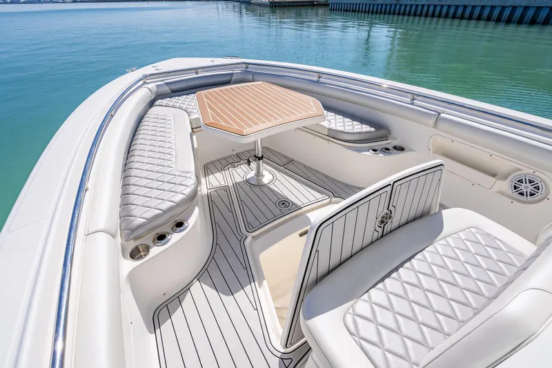 High Voltage Yacht Photos Pics 2013 Boston Whaler 320 Outrage boat interior with cushioned seating and table on calm water.