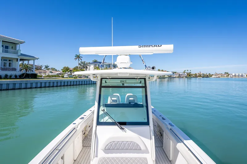 High Voltage Yacht Photos Pics 2013 Boston Whaler 320 Outrage on calm water, clear sky, luxury waterfront homes.