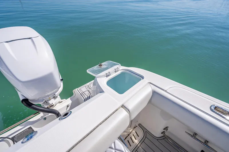 High Voltage Yacht Photos Pics 2013 Boston Whaler 320 Outrage boat with motor and open storage compartment on calm water.