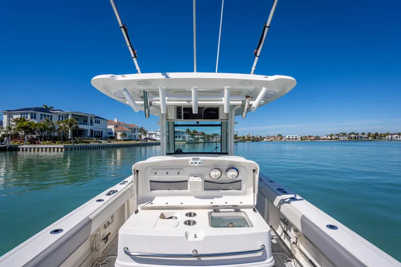 High Voltage Yacht Photos Pics 2013 Boston Whaler 320 Outrage boat on calm water, luxury waterfront homes in background.