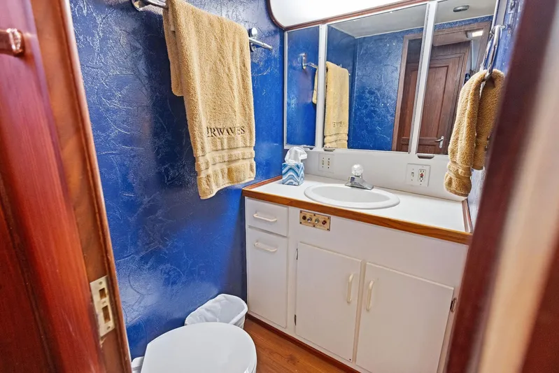 Airwaves Yacht Photos Pics Luxurious bathroom in 1987 Hatteras 68 Cockpit Motor Yacht with blue walls and white fixtures.