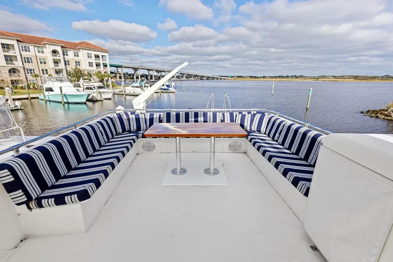 Airwaves Yacht Photos Pics 1987 Hatteras 68 Cockpit Motor Yacht with striped seating and table, docked by waterfront.