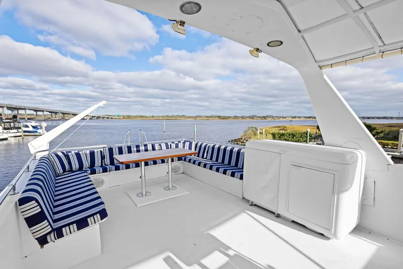 Airwaves Yacht Photos Pics 1987 Hatteras 68 Cockpit Motor Yacht with spacious deck and striped seating by the water.