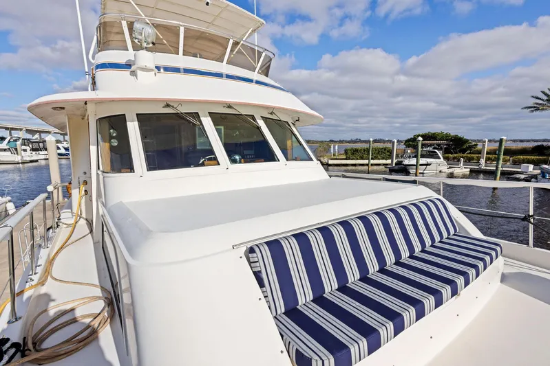 Airwaves Yacht Photos Pics 1987 Hatteras 68 Cockpit Motor Yacht with striped seating, docked under a blue sky.