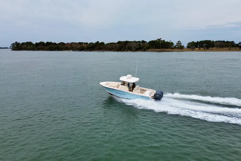 Neverland II Yacht Photos Pics 2022 Grady-White Canyon 271 boat cruising on a calm lake near a forested shoreline.