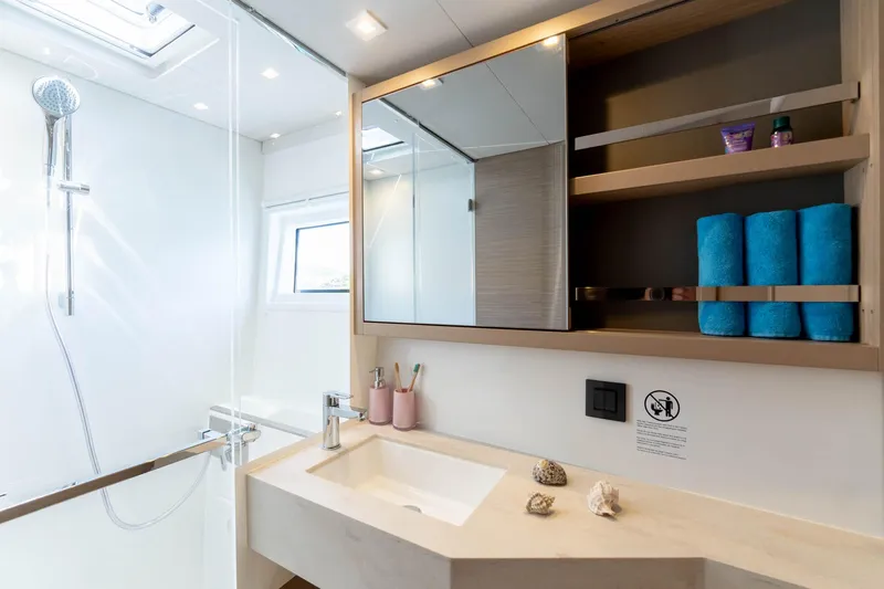 Mare Azul Yacht Photos Pics Modern bathroom in 2024 Lagoon 46 yacht with shower, sink, and storage shelves.
