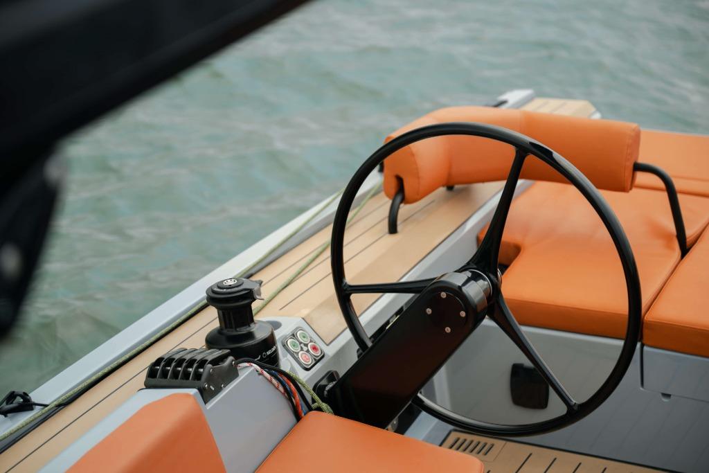 Steering wheel of 2026 Saffier SE 28 Leopard with orange seating, on calm water.