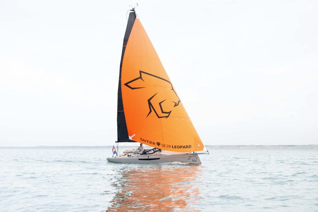 Saffier SE 28 Leopard 2026 sailboat with orange sail on calm water.