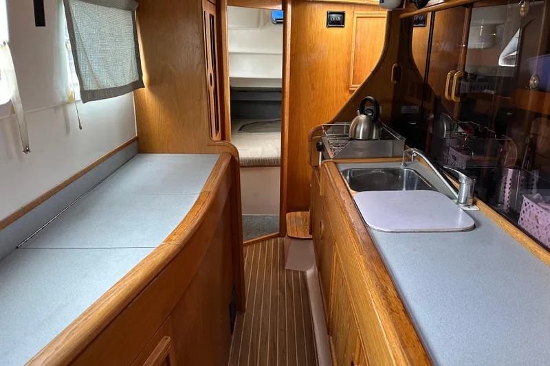 Makani Yacht Photos Pics Interior of 2008 Seawind 1000 XL catamaran with wooden cabinetry and compact kitchen area.