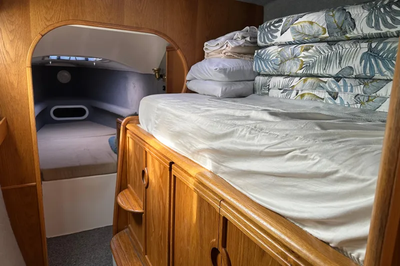 Makani Yacht Photos Pics Interior cabin of a 2008 Seawind 1000 XL catamaran with cozy bedding and wooden cabinetry.