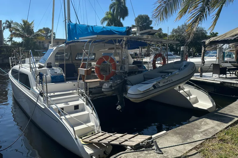 Makani Yacht Photos Pics 2008 Seawind 1000 XL catamaran docked with inflatable boat, surrounded by palm trees.