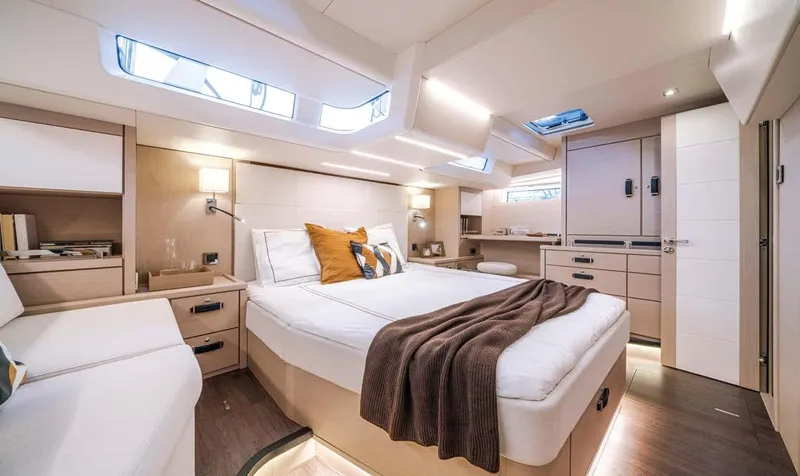  Yacht Photos Pics Luxurious interior of 2023 Jeanneau 65 Yacht with modern design and cozy bedding.