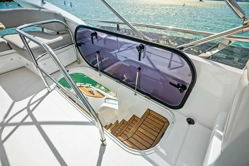 Zefa Yacht Photos Pics 2019 Princess 43 Flybridge yacht with open hatch and wooden steps, overlooking the sea.