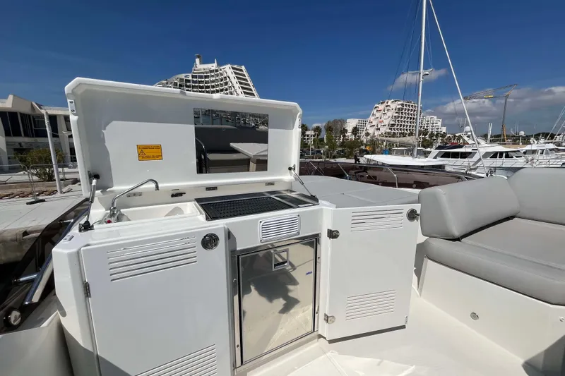  Yacht Photos Pics 2023 Prestige 520 yacht with outdoor kitchenette and seating, docked in a marina.