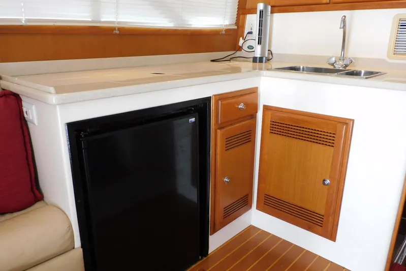 Mishap Yacht Photos Pics 1999 Cabo 35 Flybridge Sportfisher interior kitchen with sink, fridge, and wooden cabinets.