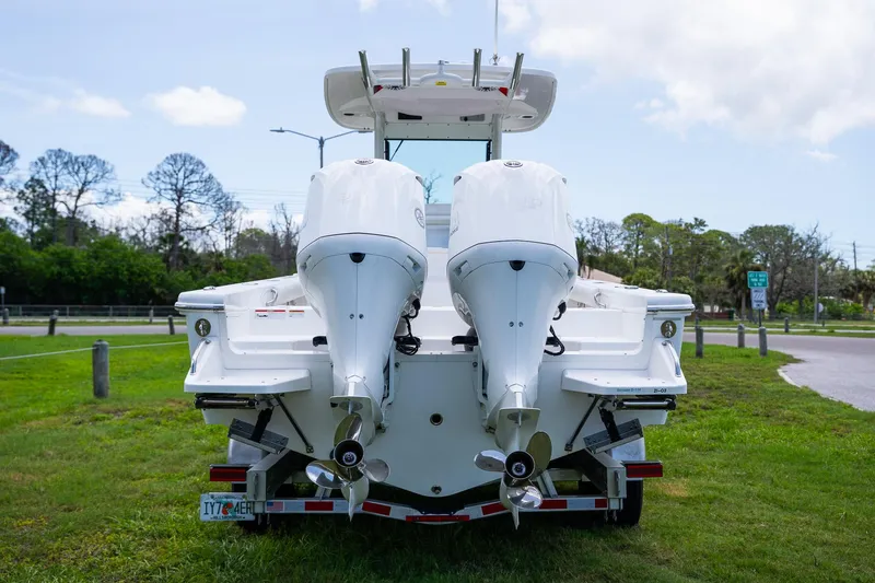  Yacht Photos Pics 2021 Everglades 273 Center Console boat with dual outboard engines, parked on grass.
