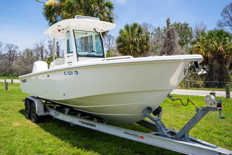  Yacht Photos Pics 2021 Everglades 273 Center Console boat on trailer, parked on grass with palm trees.