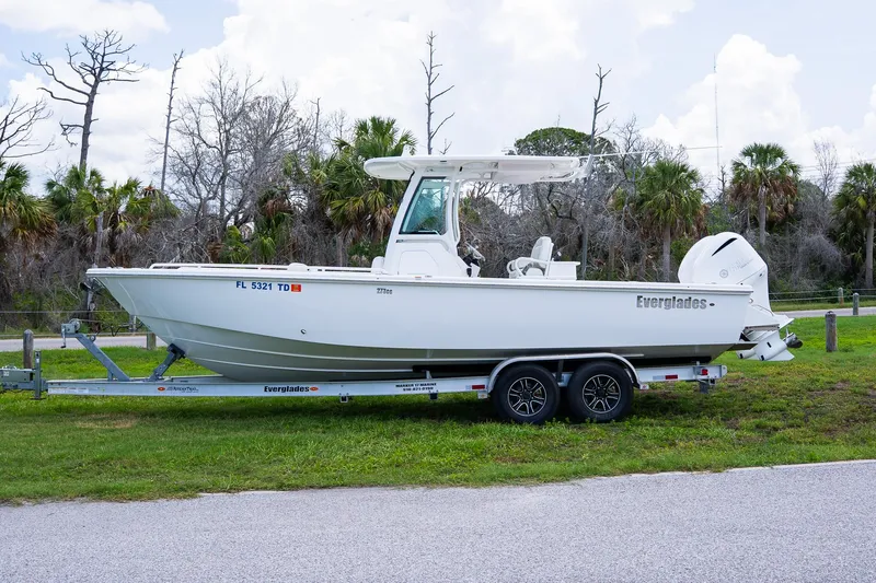  Yacht Photos Pics 2021 Everglades 273 Center Console boat on trailer, parked near trees.